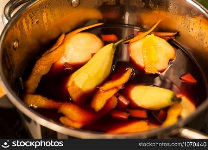 Tasty mulled red wine with pears and spices preparing in cooking pot. Closeup of Christmas holiday homemade preparation