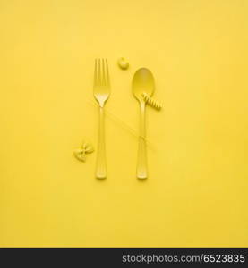 Tasty pasta.. Creative still life photo of fork and spoon with raw pasta on yellow background.