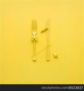 Tasty pasta.. Creative still life photo of fork and spoon with raw pasta on yellow background.