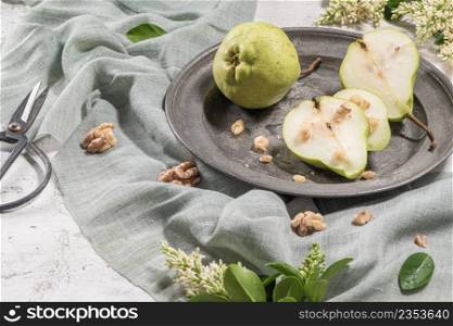 Tasty pears with nuts. A table decorated with flowers and a plate of pears cut into the plate