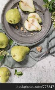 Tasty pears with nuts. A table decorated with flowers and a plate of pears cut into the plate.