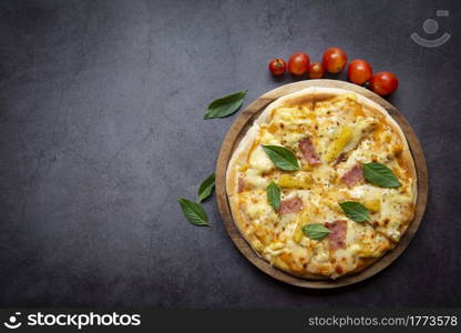 Tasty pizza homemade italian food style, pizza cheese ham and pineapple fruit cooking ingredients tomatoes basil on black background. Top view Flat lay