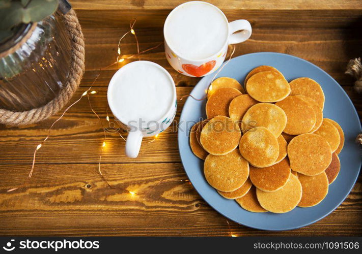 Tasty punkakes and two cups of coffee stand on a wooden tray.. Tasty punkakes and two cups of coffee stand on a wooden tray