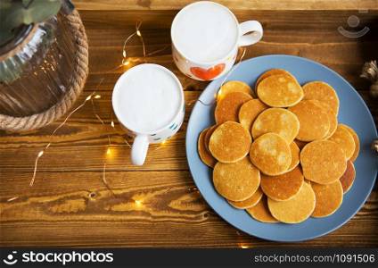 Tasty punkakes and two cups of coffee stand on a wooden tray.. Tasty punkakes and two cups of coffee stand on a wooden tray