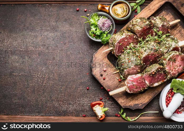 Tasty raw Meat skewers preparation with fresh delicious seasoning on rustic background, top view, border