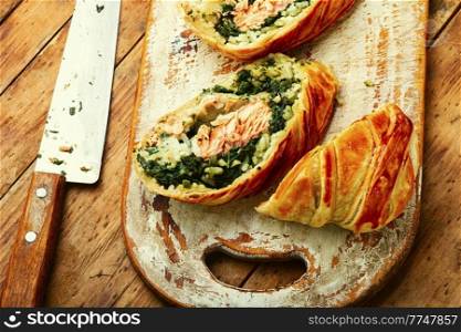 Tasty roll with salmon, rice and spinach. Fish pie. Fish wellington. Red fish in the dough.