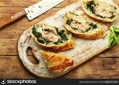 Tasty roll with salmon, rice and spinach. Fish pie. Fish wellington. Red fish in the dough.