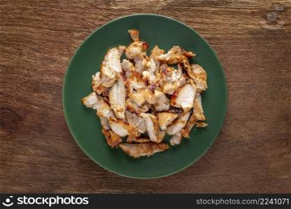 tasty slice fried pork in green ceramic plate on natural wood texture background, top view, flat lay, street food