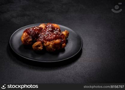 Tasty spicy chicken legs with teriyaki sauce and sesame seeds on a dark concrete background. Tasty spicy chicken legs with teriyaki sauce and sesame seeds