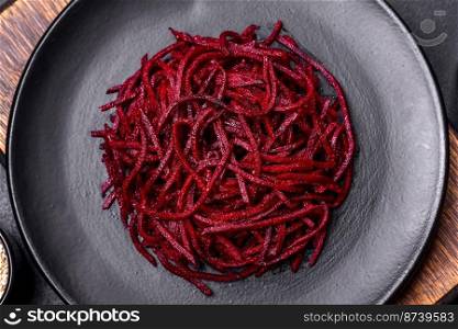 Tasty spicy Korean beet with spices and herbs on a dark concrete background. Asian food. Tasty spicy Korean beet with spices and herbs on a dark concrete background