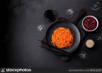 Tasty spicy Korean carrot with spices and herbs on a dark concrete background. Tasty spicy Korean carrot with spices and herbs