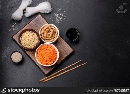 Tasty spicy Korean carrot with spices and herbs on a dark concrete background. Asian food. Tasty spicy Korean carrot with spices and herbs on a dark concrete background