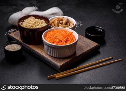 Tasty spicy Korean carrot with spices and herbs on a dark concrete background. Asian food. Tasty spicy Korean carrot with spices and herbs on a dark concrete background