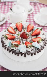 Tasty strawberry cream cake. Tasty strawberry cream cake on checkered table, with tea set