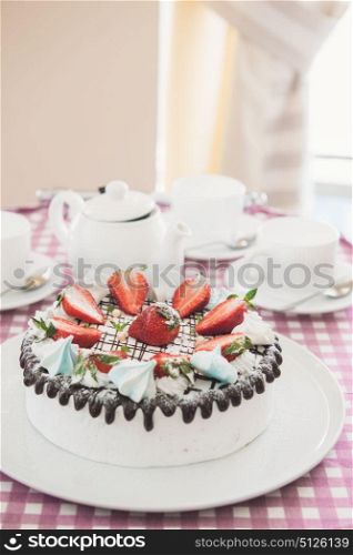 Tasty strawberry cream cake. Tasty strawberry cream cake on checkered table, with tea set