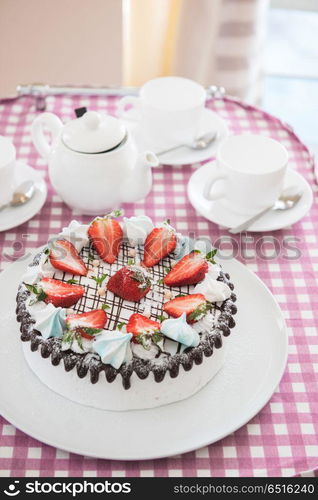 Tasty strawberry cream cake. Tasty strawberry cream cake on checkered table, with tea set