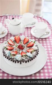 Tasty strawberry cream cake. Tasty strawberry cream cake on checkered table, with tea set