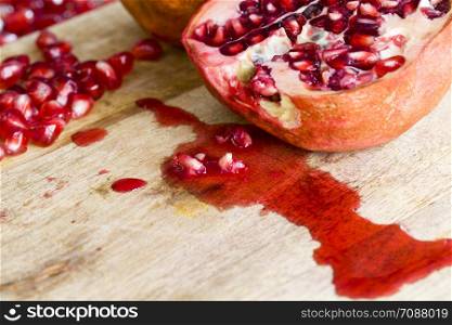 tasty sweet grains of ripe pomegranate on a wooden table, close-up of wholesome berries while breaking a whole fruit. ripe pomegranate