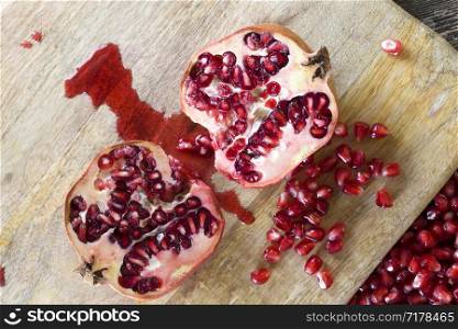tasty sweet grains of ripe pomegranate on a wooden table, close-up of wholesome berries while breaking a whole fruit. ripe pomegranate