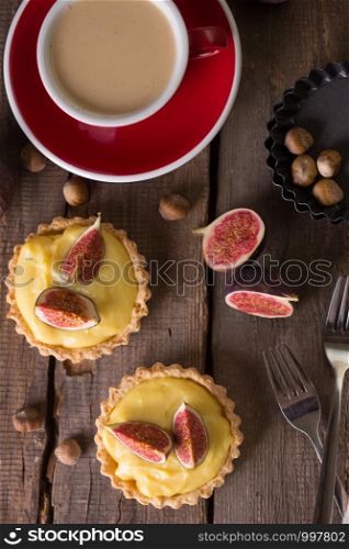 tasty tartlets with custard cream and figs with a cup of coffee