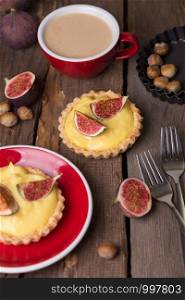tasty tartlets with custard cream and figs with a cup of coffee