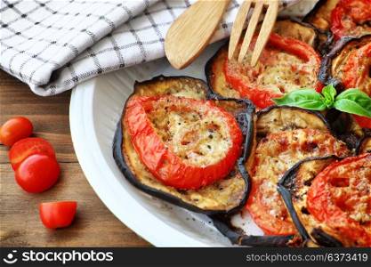 Tasty Thanksgiving meal, roasted aubergine with tomatoes and cheese on the plate on wooden table, delicious homemade food