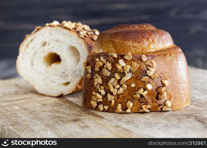 Tasty Wheat bun sprinkled with nuts and nut filling, cut on a cutting board. bun, with nut filling