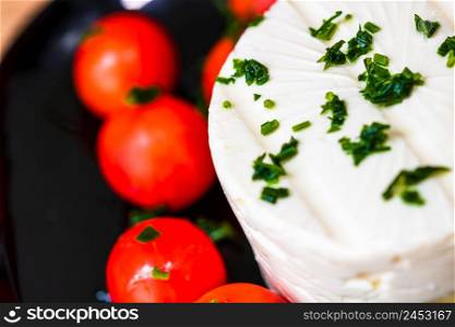 Tasty white cheese with spices and cherry tomatoes on cutting board