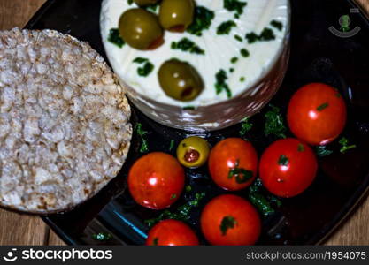 Tasty white cheese with spices, olives and cherry tomatoes on cutting board