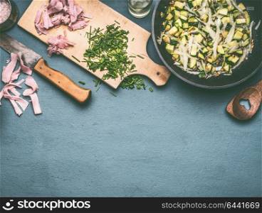 Tasty zucchini and ham dish in cooking pan on kitchen table with ingredients, top view