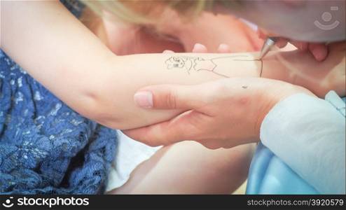 tattoo kids draw. animator draws princess on the arm of a little girl