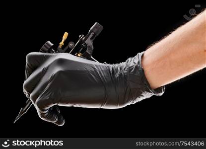 Tattoo machine in artist&rsquo;s hand isolated on black background