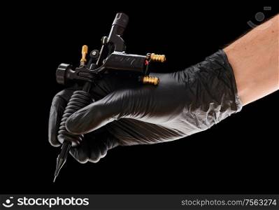 Tattoo machine in artist&rsquo;s hand isolated on black background
