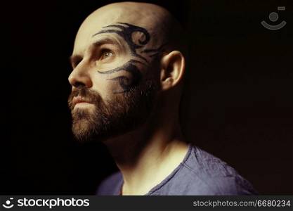 tattoo on the face, male portrait in the form of an assassin, cosplay, tattooed brutal man, guy with a tattooed face