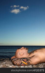 Tattooed Man Lying on Beach