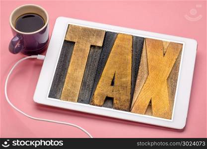 tax concept - text in vintage letterpress wood type on a digital tablet with coffee