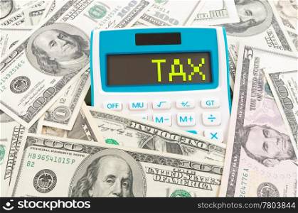 Tax concept, word on calculator with hundreds of American notes