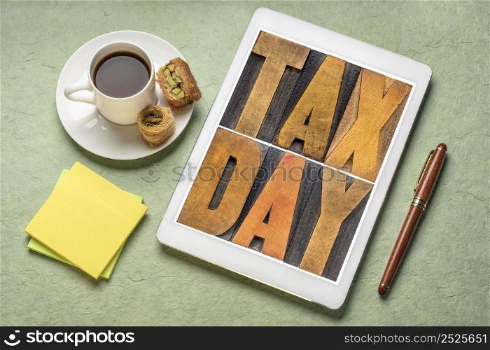 tax day concept - text in vintage letterpress wood type on a digital tablet, flat lay with with coffee, financial concept