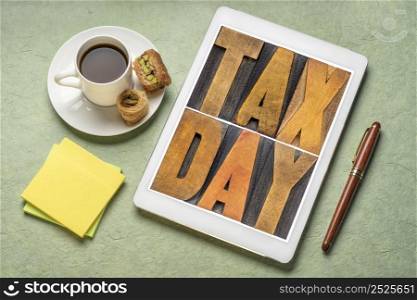 tax day concept - text in vintage letterpress wood type on a digital tablet, flat lay with with coffee, financial concept