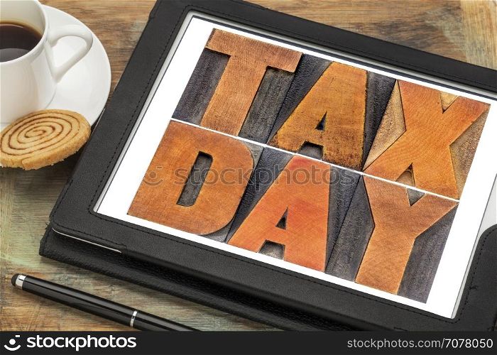 tax day concept - text in vintage letterpress wood type on a digital tablet with coffee