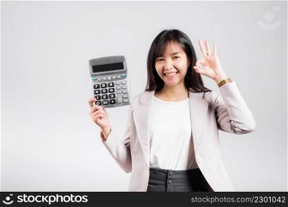 Tax day concept. Woman confident smiling holding e≤ctronic calculator and show OK≥sture, excited happy Asian fema≤studio shot isolated on white background, Account and finance counting income