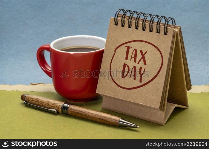 tax day note- handwriting in a spiral desktop calendar with a cup of coffee - business financial concept or reminder