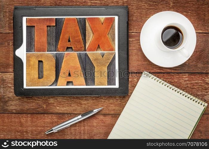 tax day word abstract in vintage letterpress wood type on a digital tablet with coffee and notebook