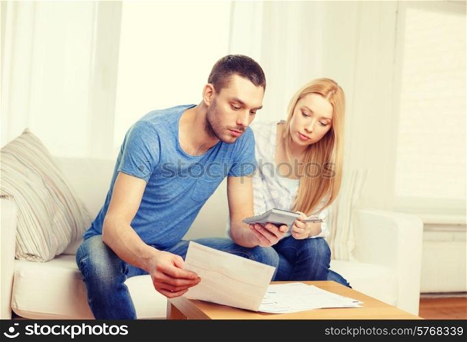 tax, finances, family, home and happiness concept - busy couple with papers and calculator at home