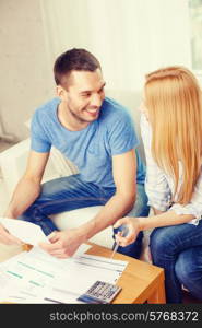 tax, finances, family, home and happiness concept - smiling couple with papers and calculator at home