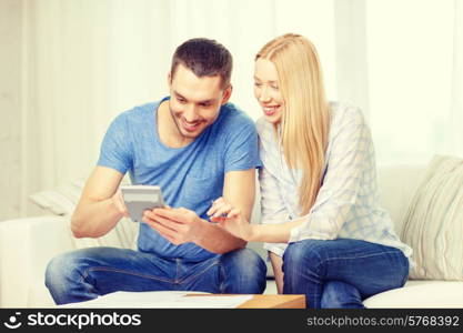 tax, finances, family, home and happiness concept - smiling couple with papers and calculator at home