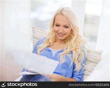 tax, finances, home and happiness concept - smiling young woman with papers at home