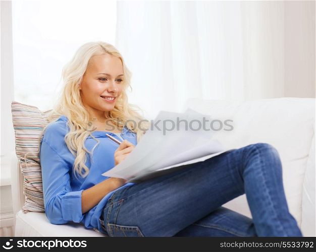 tax, finances, home and happiness concept - smiling young woman with papers at home