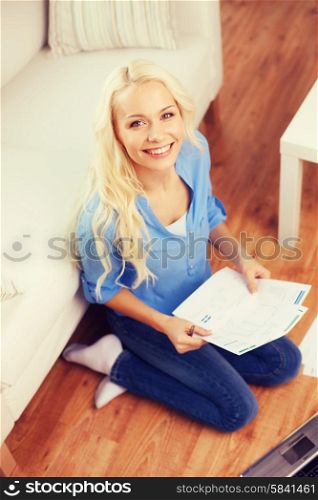 tax, finances, technology, home and happiness concept - smiling young woman with papers and laptop computer at home
