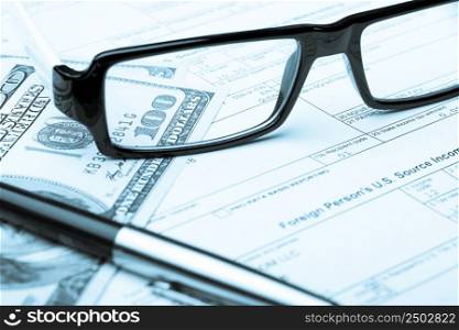 Tax form with dollar bills through glasses